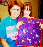 Joyce Ponder and her granddaughter Katy, holding up the quilt she was making at CS that week.