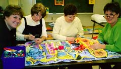 Teachers bind the edges of the first mural made into a quilt sandwich. ©Susan Shie 2001.